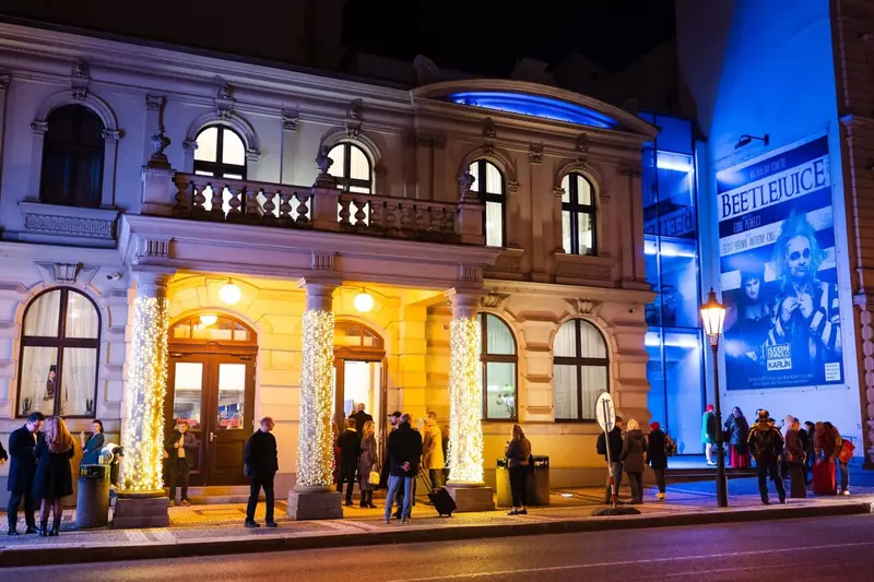 Večerní průčelí historického divadla se světelnými sloupy